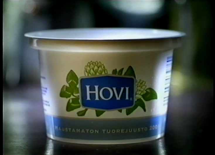 Close-up of scooped white cheese, the blue Valio flag mark in the corner