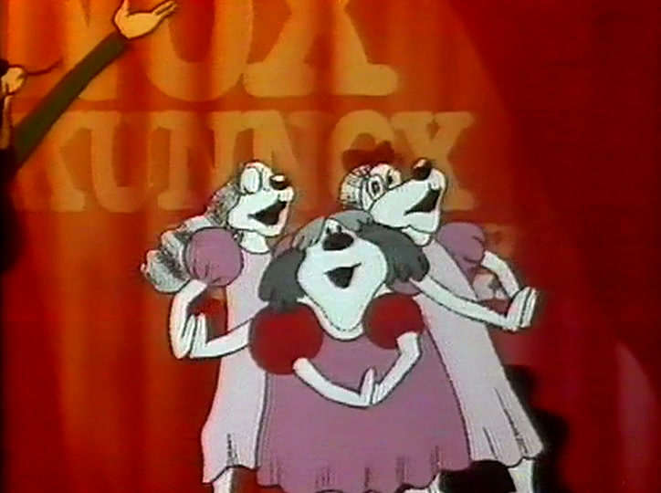 A line of dogs in pink dresses dances on a stage, red curtain behind them.