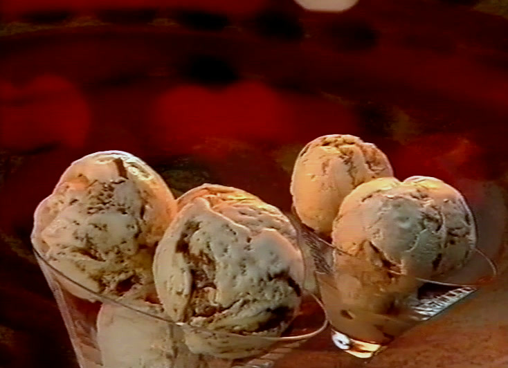 Glass dish of nut-rippled ice cream against a deep red painted ground, La Gala logo above