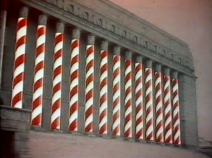 The columns of a long public building read as red and white candy stripes.