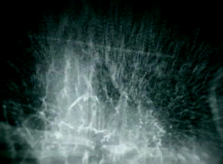 Tilted view down a wet road, a car speeding away at top right and throwing spray