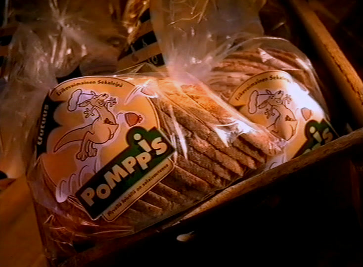 Wrapped Pomppis loaves in a wooden crate behind a card reading perhe leipurit