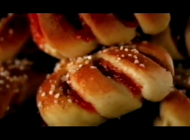 Sugared buns split along the top with red jam, shot close against a dark background