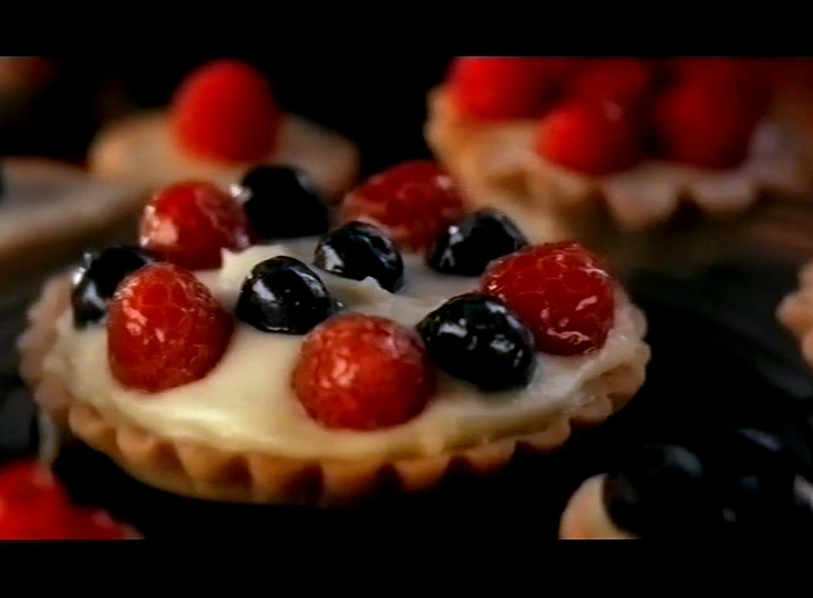 A tart of raspberries, blackcurrants and white cream, more of them out of focus behind