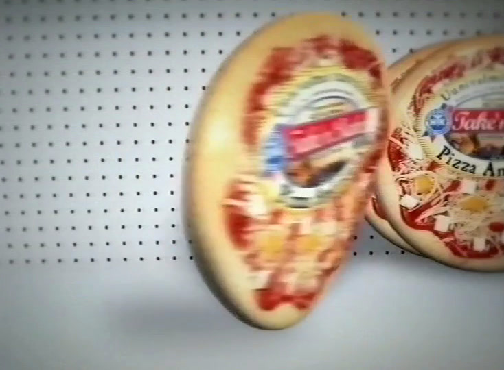 One pizza stands on its edge and turns, its label blurred by the movement