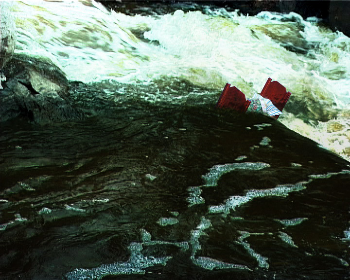 A red accordion floats half submerged in dark water below white rapids.