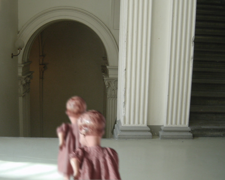 Two dolls in dusty pink dresses walk through a pale hall past a fluted column.