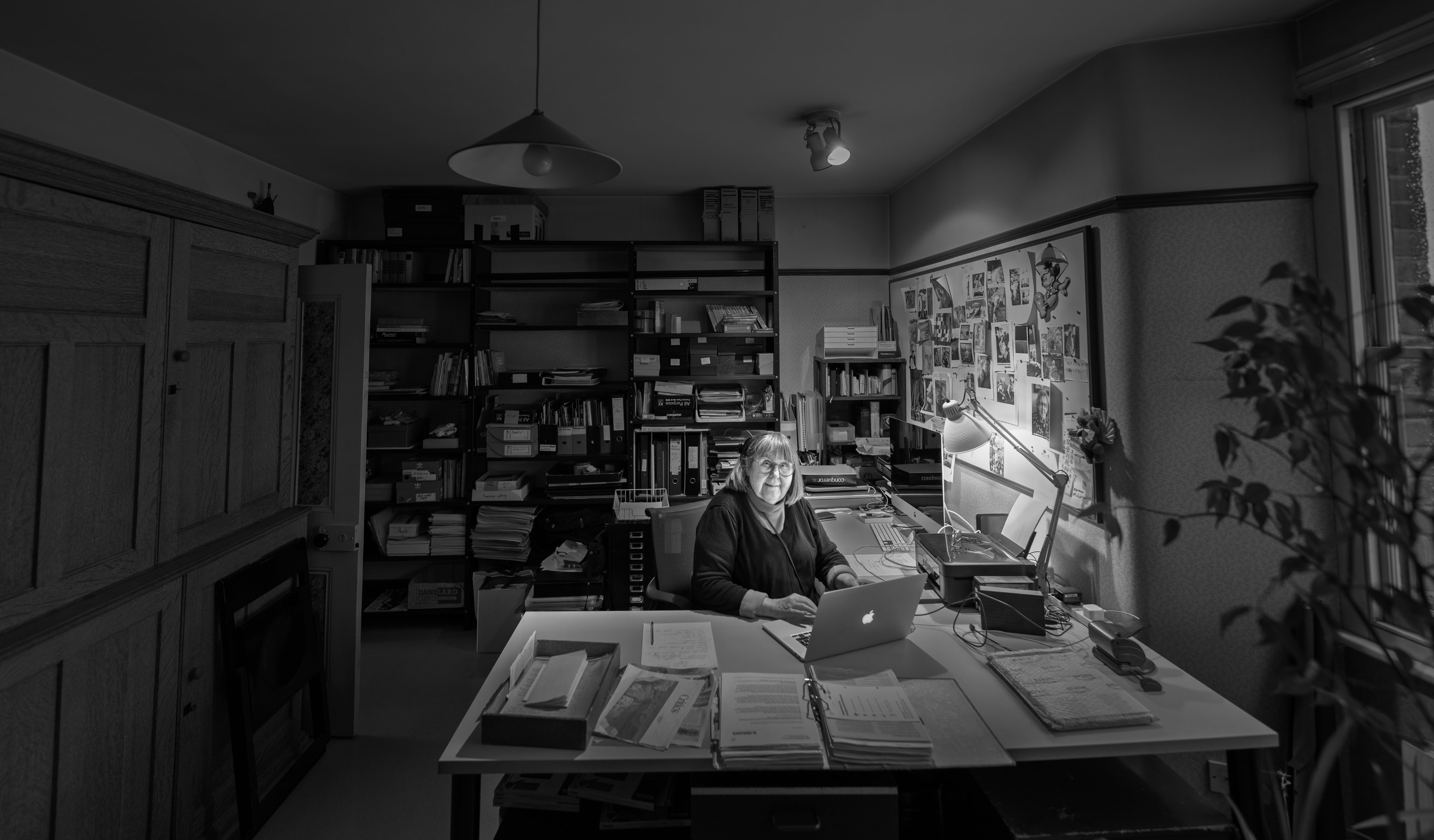 Marjut Rimminen at her desk in her London studio, surrounded by archive shelves and a pinboard of clippings
